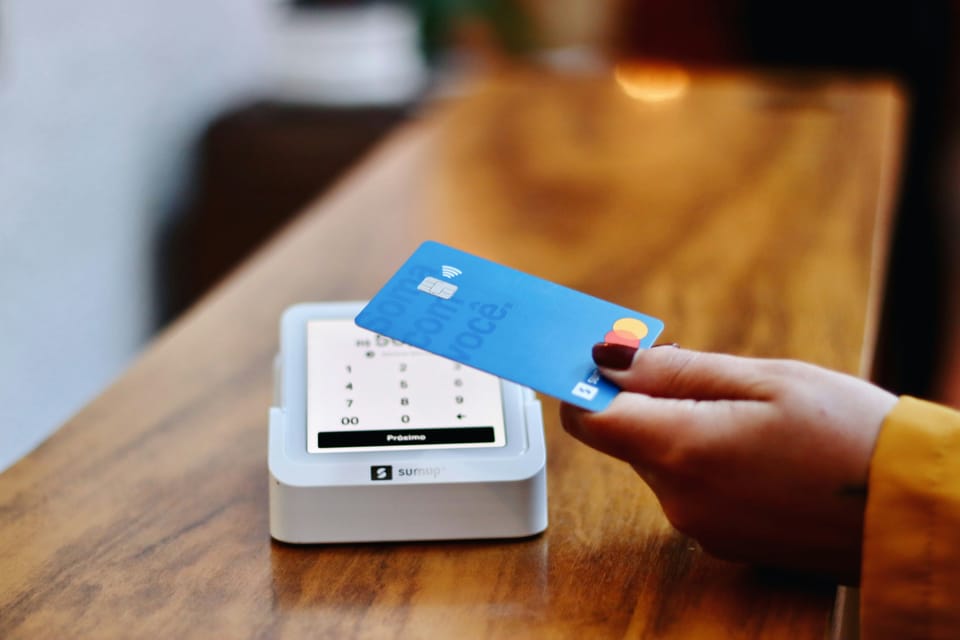 A person uses a mastercard credit card for tap to pay on a sumup card reader
