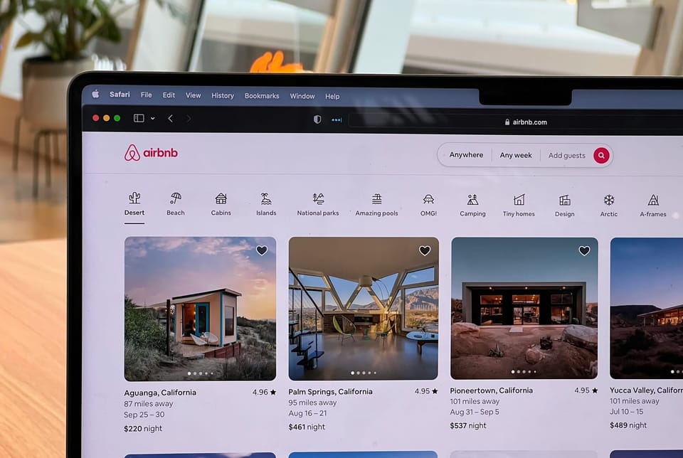 A computer on a web browser showing listings for Airbnb.