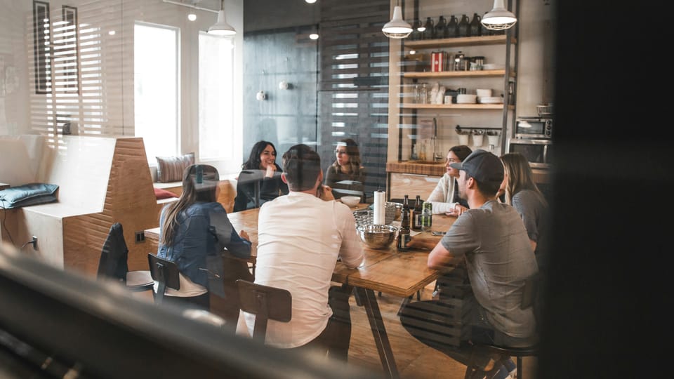 A group of people sit around a table in a meeting room.