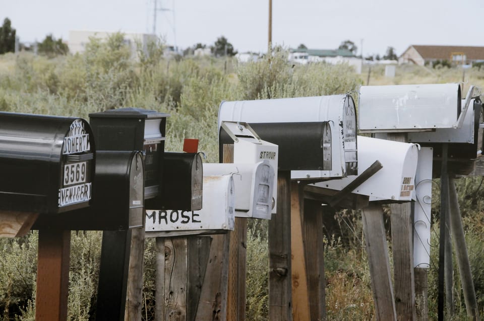 A group of mail boxes on posts by the side of the road.
