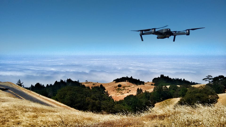 A drone flying over hills with clouds in the distance. StirlingX is a drone startup
