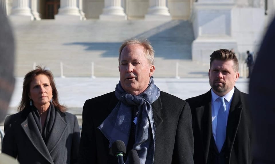 Texas Attorney General Ken Paxton holding a press conference outside a court building.