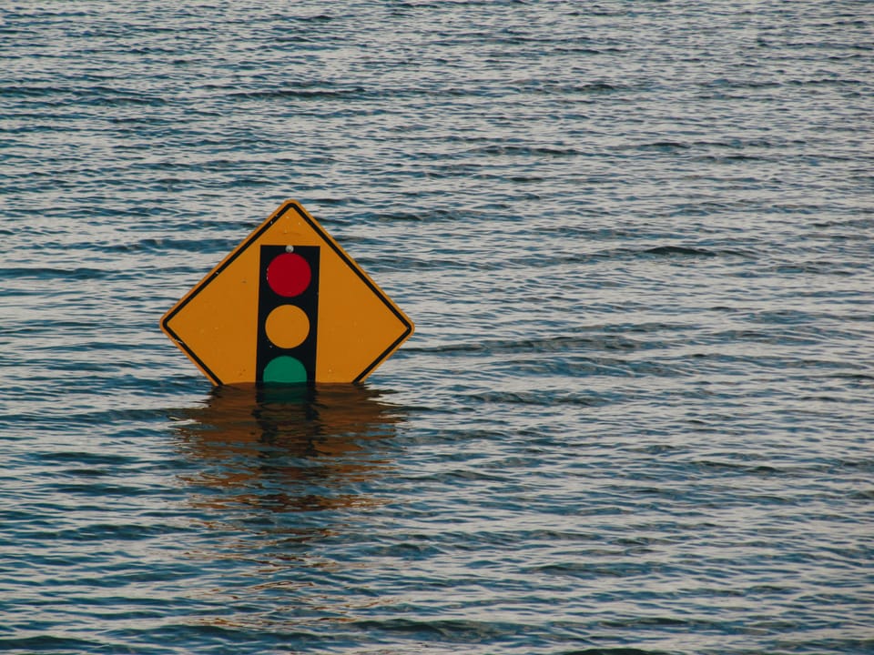 A traffic light sign pokes out of flood water. NS&I's £3 billion IT transformation project has been a disaster say MPs